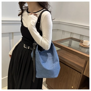 Gros plan détaillé du sac seau en denim bleu avec bandoulière noire dans un cadre élégant