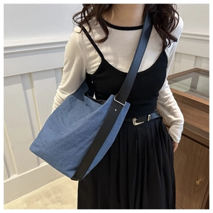 Detailansicht der großen Denim-Hobo-Tasche mit Lederriemen und Metallschnallen am Model