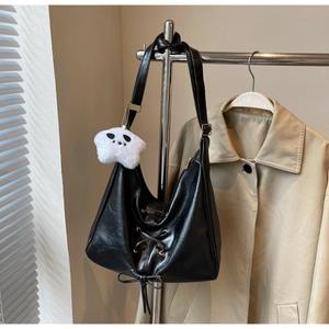 Detail of black PU leather shoulder bag with criss-cross laces and star plush pendant