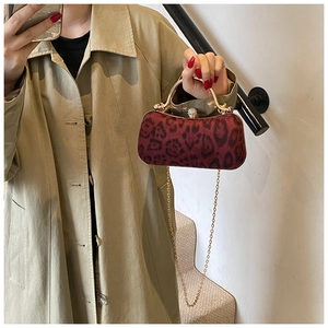 Detail der burgunderroten Clutch mit Leopardenmuster, Goldgriff und Perlenverschluss