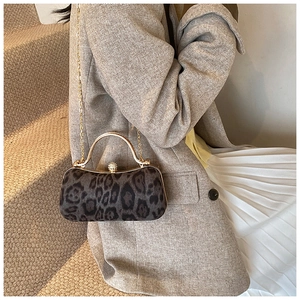 Leopard print clutch with gold metal handle and pearl clasp on model's shoulder