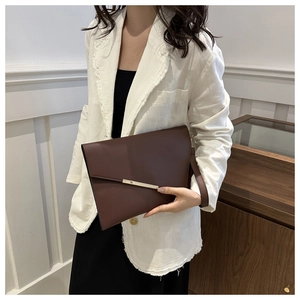 Detail of dark brown envelope clutch bag with gold bar buckle and wristlet strap