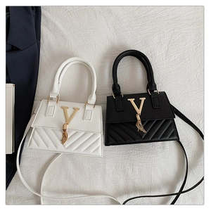 Detail of white and black crossbody bags with V-shaped quilting and golden tassel