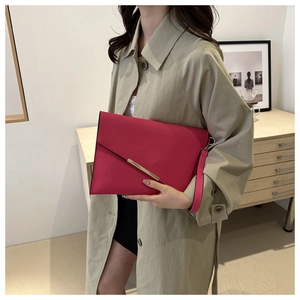 Chic magenta envelope clutch with gold metal trim and wristlet strap shown with trench coat