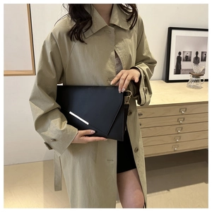 Detail of black envelope clutch with asymmetric flap and silver metallic trim detail