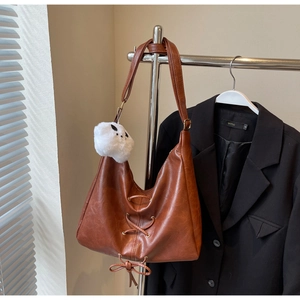 Brown leather Hobo bag with cross-lace bow detail and a white plush cat charm