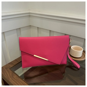 Detail of fuchsia envelope clutch with gold metal bar and wristlet on wooden table