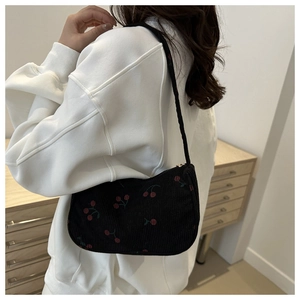 Detailed view of black corduroy underarm bag featuring delicate cherry embroidery
