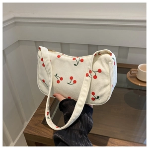 Dettaglio della borsa sottobraccio in velluto a coste crema con stampe di ciliegie rosse