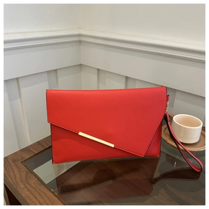 Detail of red envelope clutch bag with gold trim and matching wrist strap