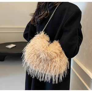 Nahaufnahme der beigen Plüschtasche mit Goldkette auf einem schwarzen Mantel