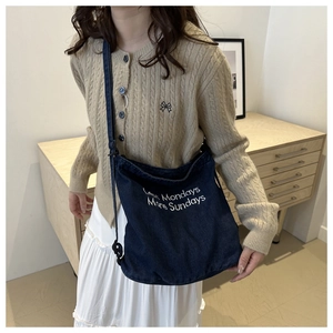 Close-up of embroidered Less Mondays More Sundays text on dark blue denim tote bag