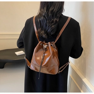Brown glossy leather drawstring bucket backpack with silver butterfly metal detail