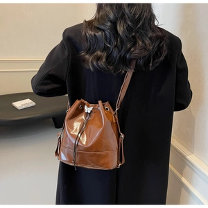 Detail of a brown glossy PU leather bucket bag with a white butterfly charm