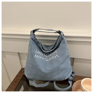Detailed close-up of blue denim tote bag with Less Mondays More Sundays white embroidery