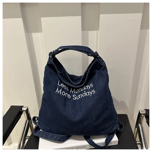 Detail of blue denim tote bag with Less Mondays More Sundays white embroidery