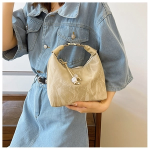 Sac boulette en cuir plissé beige avec poignée en métal et pompon porté avec du denim