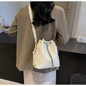 Minimalist cream white leather bucket bag with silver butterfly charm shown on model