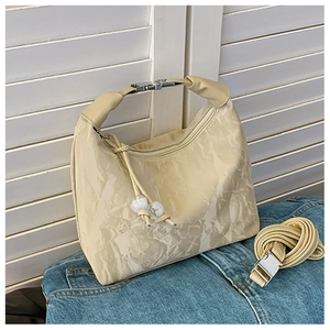 Détail du sac hobo plissé crème avec boucle argentée et perles décoratives blanches
