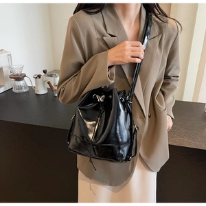Detail of glossy black patent leather bucket bag with silver butterfly drawstring