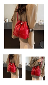 Detail of red glossy bucket bag with drawstring closure and white butterfly hardware