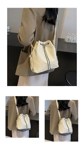 Detailed close-up of cream-colored drawstring bucket bag with silver butterfly charm