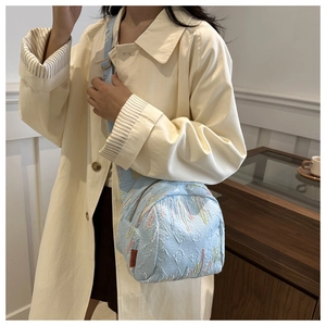 Détail de la besace matelassée bleu clair avec broderie et étiquette fashion orange