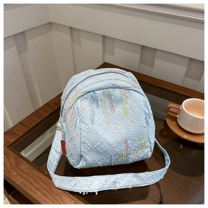 Sac bandoulière matelassé bleu clair avec broderie arc-en-ciel et étiquette sur table en bois