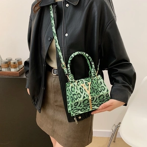Mini borsa leopardata verde con logo V dorato e nappina indossata da una modella