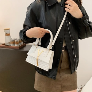 White quilted leather crossbody bag with gold V logo and tassel detail on female model