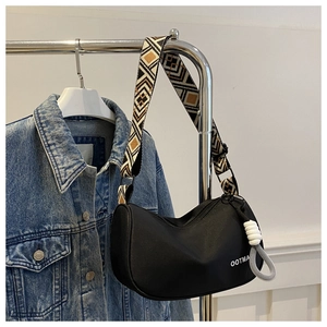 Close-up of black crossbody bag with geometric pattern wide shoulder strap detail