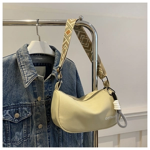 Detail of beige crescent underarm bag with geometric wide strap and OOTMAO lettering