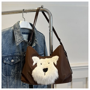 Détail du sac en similicuir marron café avec motif chiot en peluche blanche sur fond en denim