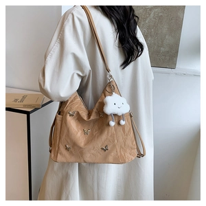 Detail of silver butterfly buckles and plush cloud charm on a brown nylon shoulder bag