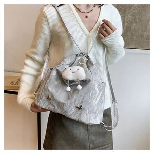 Silver metallic tote bag detail with golden butterfly accent and plush cloud charm
