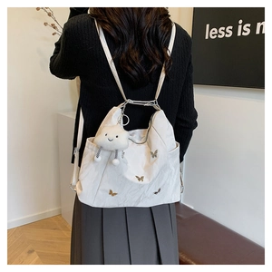 White versatile tote with golden butterfly charms and a plush smiley cloud pendant