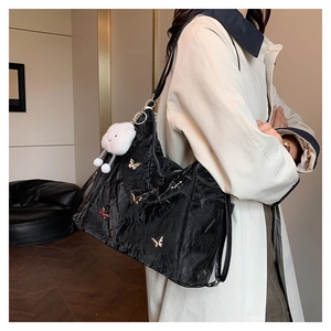 Detail of black pleated tote bag with metal butterfly charms and fluffy cloud pendant