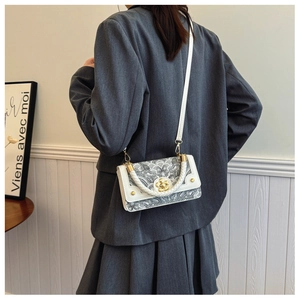 Gedetailleerd zijaanzicht van de retro crossbodytas op een model met een grijs jasje