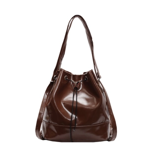 Dark brown patent leather bucket bag with drawstring closure and metal butterfly clasp