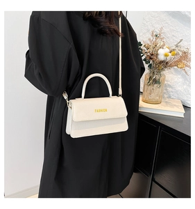 Detail einer weißen strukturierten Lederhandtasche mit gelbem Fashion-Text auf der Klappe