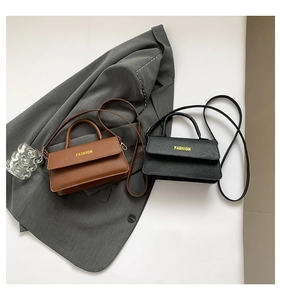Detail view of lychee pattern leather bags in brown and black on a grey suit jacket