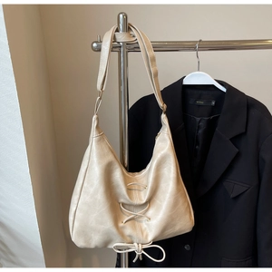 Detail of cream white Hobo bag featuring decorative criss-cross lacing and bow ornament