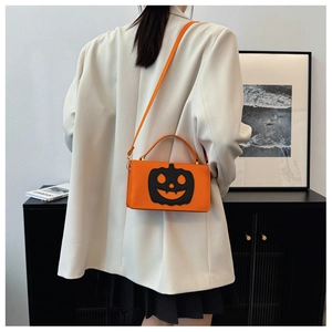 Chic orange pumpkin crossbody bag styled with a beige blazer and black pleated skirt