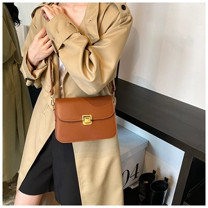 Detailed close-up of brown leather crossbody bag with square gold metal lock and strap