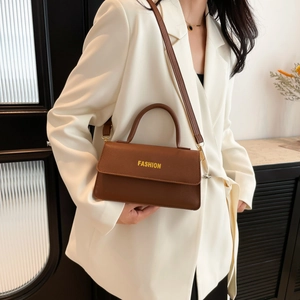 Braune Leder-Umhängetasche mit Fashion-Logo, präsentiert an einem weißen Blazer-Modell