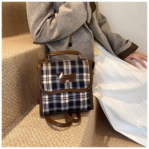 Close-up of British style checkered bag with embroidery and dark brown leather handle
