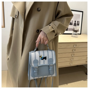 Close-up of small blue striped crossbody bag with cute dog embroidery and leather strap