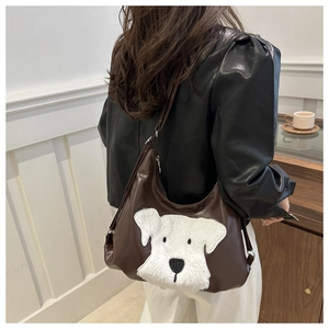 Détail d'un sac cabas en cuir marron avec patch de chien en peluche sur un mannequin