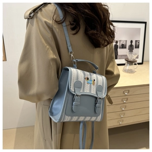 Détail du sac à dos bleu clair avec broderie de chien et tissu texturé porté par un modèle