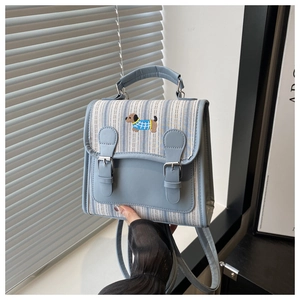 Détail d'un sac en toile rayé bleu clair avec broderie chiot et fermeture à double boucle